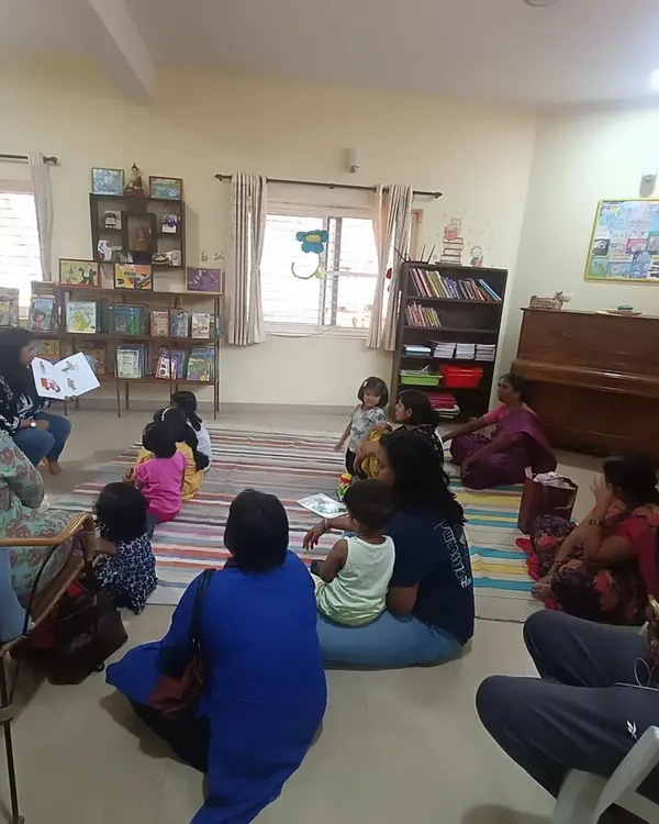 Welcome to our cozy reading lounge, where children and parents gather on the floor for an immersive storytelling experience. This is where we build a community around the shared love for stories.