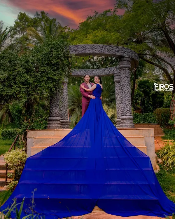 A stunning sunset shot with a dramatic flowing gown. The vibrant colors of the sky and the dress create a powerful, cinematic pre-wedding portrait.