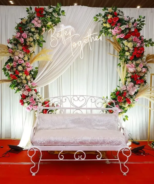 This elegant anniversary stage combines a floral ring backdrop with custom neon signage and classic seating. We focus on creating a picture perfect focal point for your celebration, ensuring every photo captures the magic of the moment.