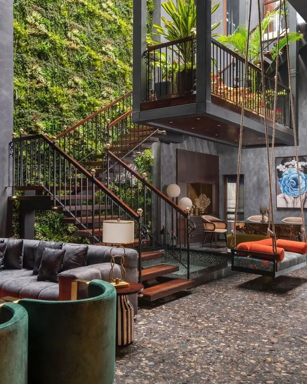 This double-height living space from our Utopia project embodies our approach to biophilic design. We integrated a dramatic vertical garden, a suspended swing, and a tranquil water body to create a home that breathes, turning a landlocked plot into a lush, vertical oasis.