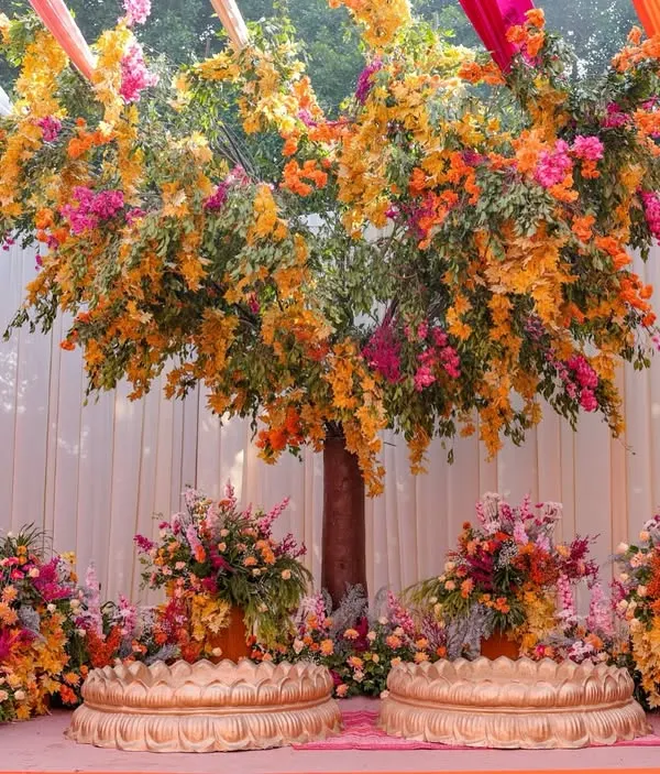 For this Haldi, I designed a magnificent 'tree of life' as the centerpiece, blooming with vibrant orange and pink flowers, creating a stunning and meaningful backdrop for the couple.
