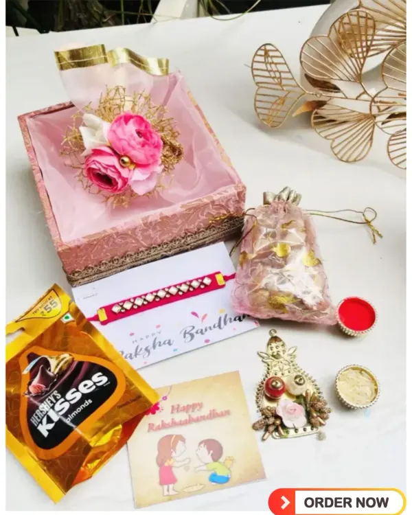 A complete Rakshabandhan gift set in a beautiful pink brocade box. This hamper includes a rakhi, a greeting card, Hershey's Kisses, a potli of dry fruits, and traditional roli-chawal for the ceremony.