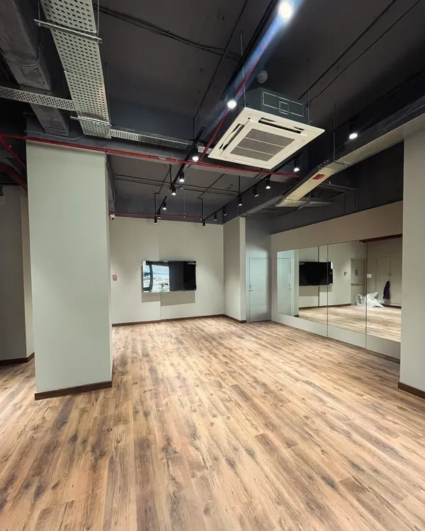 This wide angle shows the full expanse of the studio. You can see how the mirrors on the wall create a great sense of depth, making the space feel even larger and more dynamic. It's an ideal setup for large group activities or workshops.