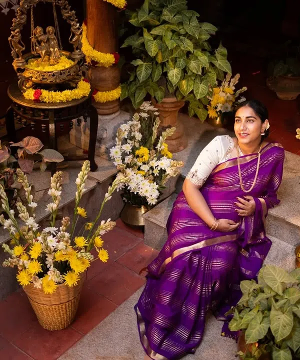 A beautiful portrait of an expecting mother in a traditional setting, surrounded by flowers and brass decor, capturing the essence of her maternity journey.