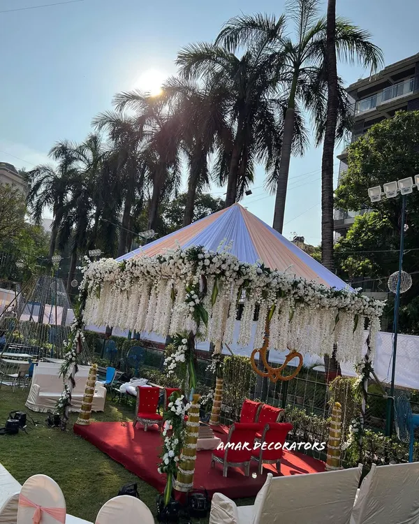A beautiful shot of a sunset wedding ceremony I designed. The mandap is draped in white fabric with hanging floral strings, creating a serene and heavenly space for the couple to take their vows as the sun goes down.