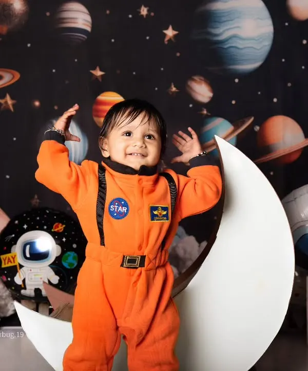 A joyful little astronaut celebrating his first birthday, standing proudly on the moon in our outer space set.