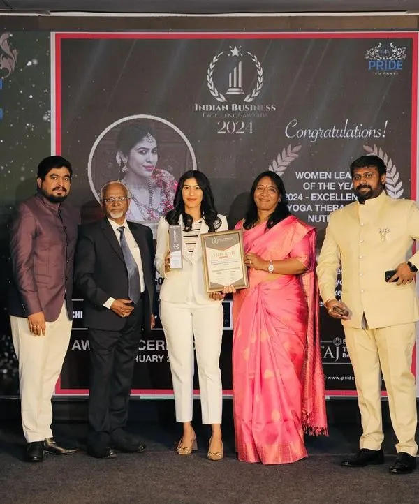On stage accepting the Pride India Award for 'Women Leader of the Year'. This moment celebrates the fusion of ancient healing practices with modern wellness, a philosophy I bring to every client session.