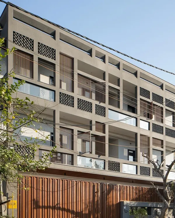 This is the Urban Oasis, a home designed as a modern bastion in Hapur. Its facade is a hard shell with a soft core, using a grid of raw concrete and fly ash bricks to shield the interiors from a harsh industrial environment while allowing light and air to flow freely, creating a breathable, tranquil sanctuary within.