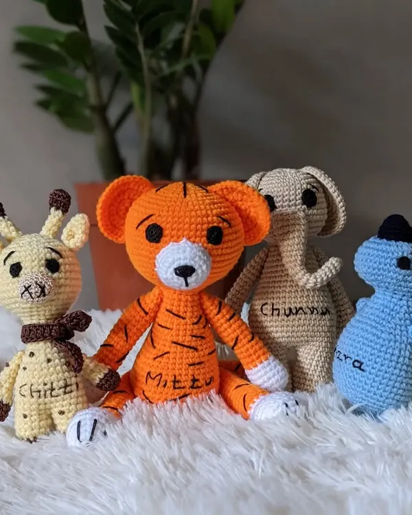 A custom set of animal friends, including a giraffe, tiger, elephant, and dinosaur, each personalized with an embroidered name.