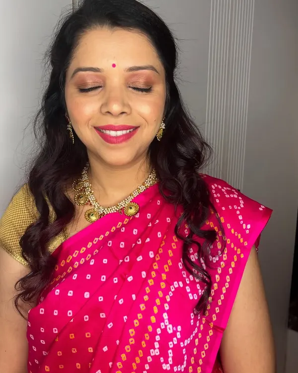 A close-up of Anita's festive makeup. The look is natural and radiant, with a focus on glowing skin, a touch of shimmer on the eyes, and a pretty red lip.