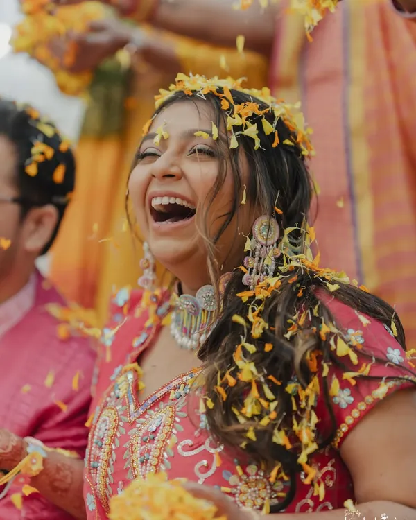 A bride's infectious laughter during her Haldi ceremony as she's showered with flower petals. This is the kind of pure, unscripted joy we love to capture.