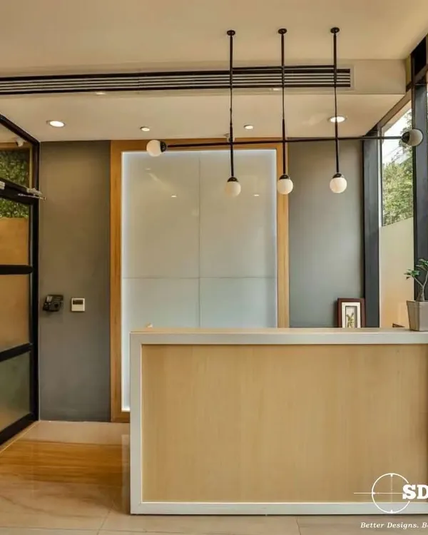 This reception area design combines a simple wooden desk with elegant globe lighting and glass walls. The result is a bright, airy, and professional space that immediately puts visitors at ease.