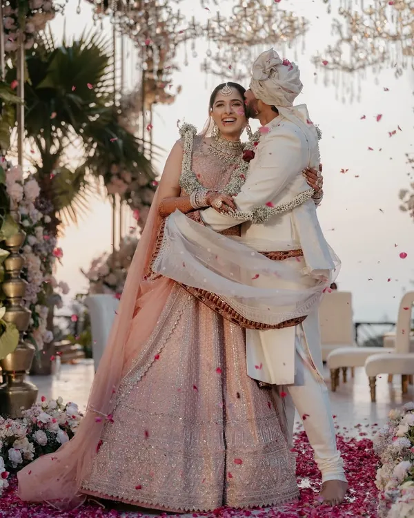 A moment of pure joy. This bride's pastel pink lehenga is paired with soft pink makeup tones and a clean bridal bun, creating a fresh and modern Phera look.