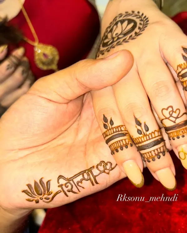 A beautiful moment between a couple, each getting a personalized mehndi design. She has his name on her hand, and he has hers, a simple yet powerful symbol of their bond.