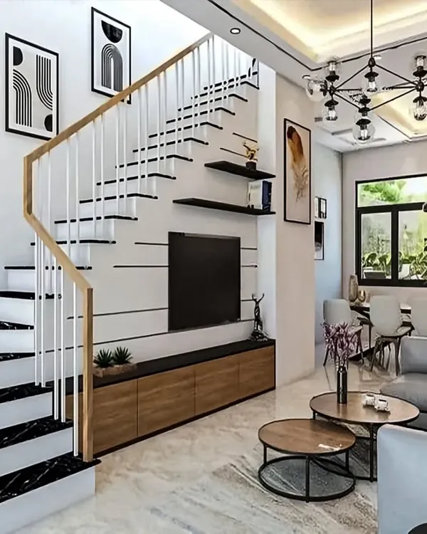 This open-plan living area features a TV unit integrated with the staircase, a clean and space-efficient solution. The design uses a monochrome palette with black marble steps and light wood accents for a contemporary look.