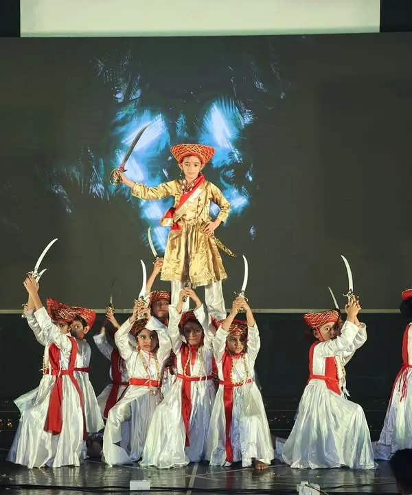 This is a powerful moment from our "Tanaji" act, a historical tribute performance. The lead performer is lifted by the group, holding swords to create a dramatic and heroic pose.