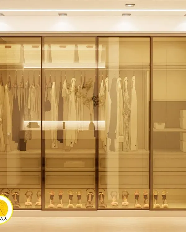A stunning walk-in closet with tinted glass sliding doors and internal lighting. This custom modular wardrobe provides a clear view of the organized clothes and accessories, adding a touch of luxury to the bedroom.