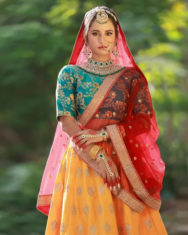 This Heeramandi-inspired look is a great example of a full thematic collaboration. The rich colors of the yellow, red, and teal lehenga stand out beautifully against the lush green outdoor background, creating a regal portrait.
