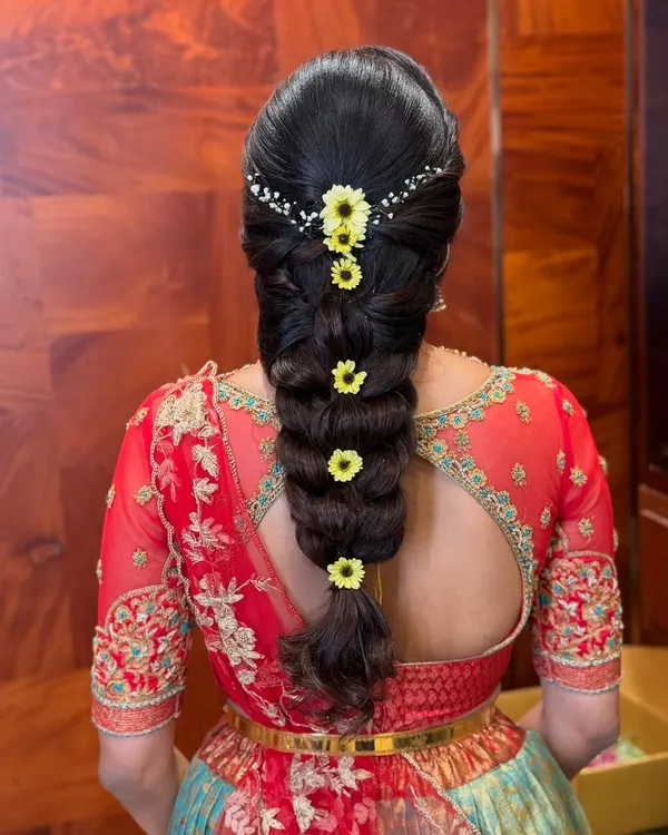 A classic South Indian bubble braid, neatly sectioned and adorned with fresh yellow flowers and a delicate hair accessory. This style is both traditional and chic.