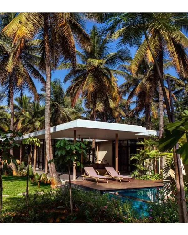 This vacation home, nestled among a dense grove of coconut palms, is designed to feel like a natural extension of the landscape. The simple, low-slung roofline keeps the focus on the surrounding beauty.