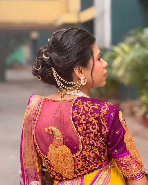 This is a classic Maharashtrian bridal bun, which I have elevated with traditional crescent moon accessories and a delicate chained 'kaan vel'. The intricate twists of the bun are designed to hold securely under a dupatta, making it a perfect choice for a traditional wedding ceremony.