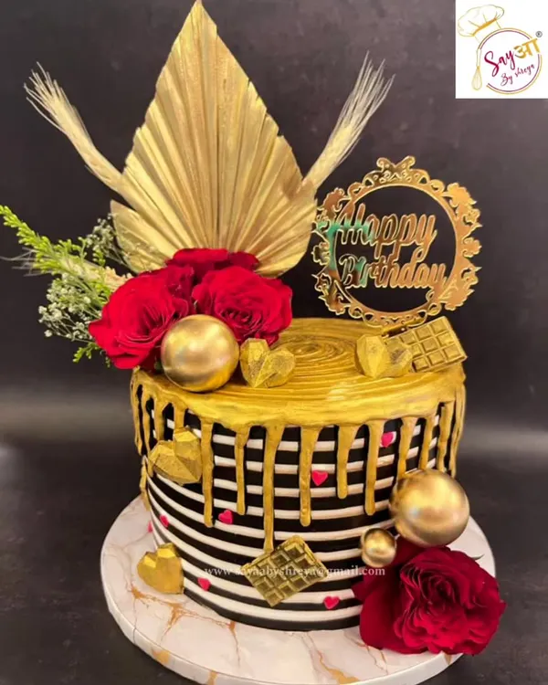 This black and white striped cake with a dramatic gold drip is a statement of modern elegance. Adorned with red roses, gold hearts, and dried palm spears, it's a luxurious centerpiece for a sophisticated birthday.