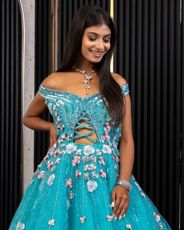 A closer look at our stunning off-the-shoulder blue gown. The intricate lacework on the corset-style bodice and the scattered floral details on the tulle skirt are designed for a true princess moment.