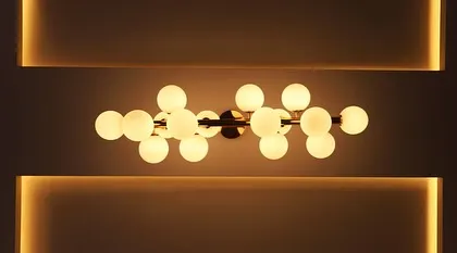 A modern, sculptural chandelier with globe lights, set within a cove-lit ceiling. This type of lighting serves as both a functional fixture and a piece of art.
