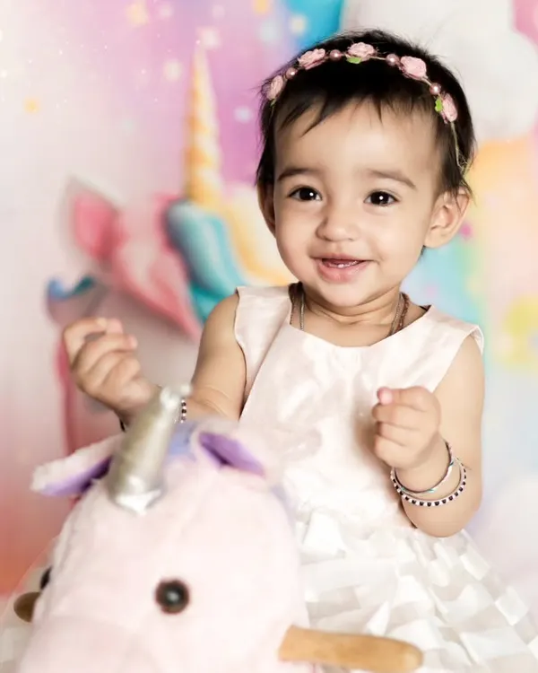 A close-up of this sweet girl's happy smile during her unicorn-themed photoshoot. The pastel rainbow background and her gentle expression make this a truly magical portrait.