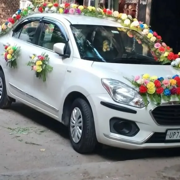 A wedding car decorated with bouquets of colorful artificial flowers on the hood, roof, and doors.