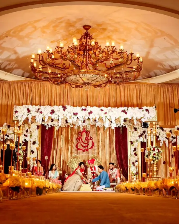 A traditional Hindu wedding ceremony under a grand chandelier in our ballroom. The space is designed to accommodate large gatherings while maintaining a sense of warmth and intimacy, with golden drapery and floral arrangements creating a sacred and celebratory atmosphere.