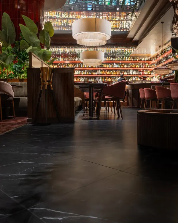 The flooring is the foundation of this restaurant's atmosphere. For Hikki, I selected a large-format black marble-style tile with subtle white veining. This choice provides a sleek, sophisticated base that grounds the vibrant red wall tiles and warm wood furnishings, creating a balanced and moody ambiance.