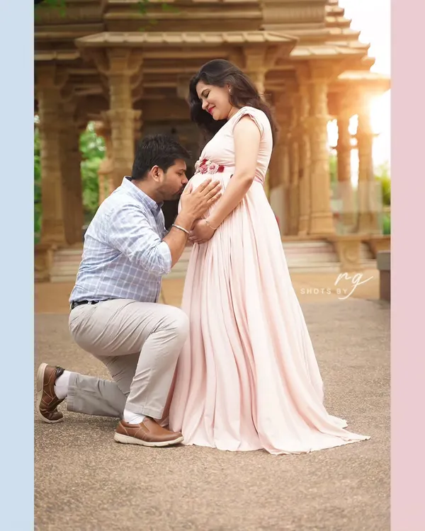 A tender kiss for the baby on the way. This outdoor couple's portrait captures the love and anticipation that fills this special time, set against a beautiful architectural backdrop.