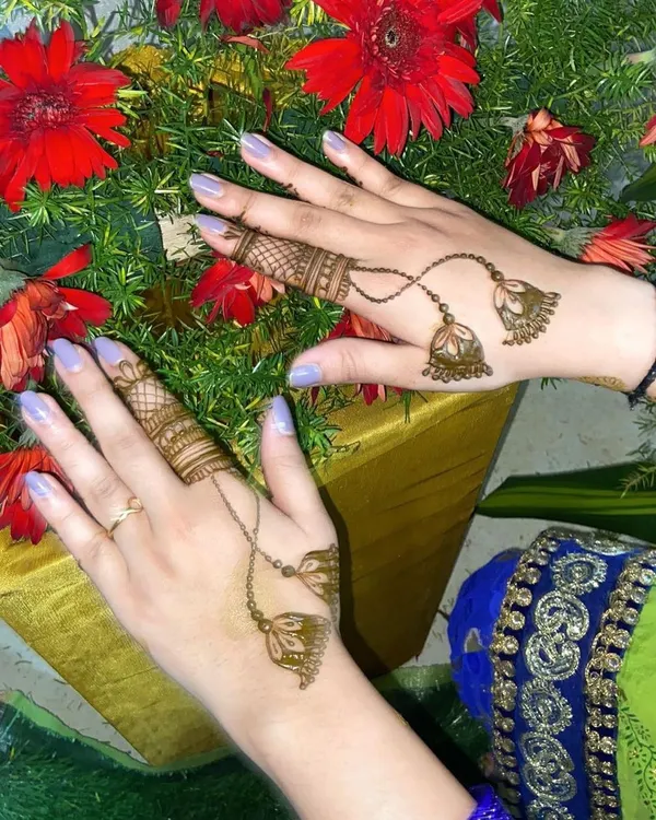 A creative and minimalist design featuring henna jhumkas (earrings) that appear to dangle from detailed finger bands.