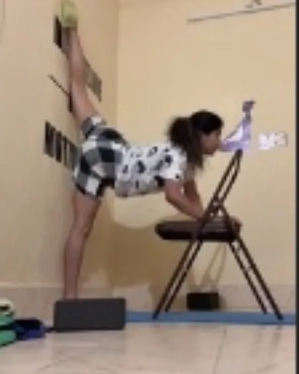 Using a chair, blocks, and the wall to work on a standing split variation. This setup provides stability and allows me to focus on the stretch.
