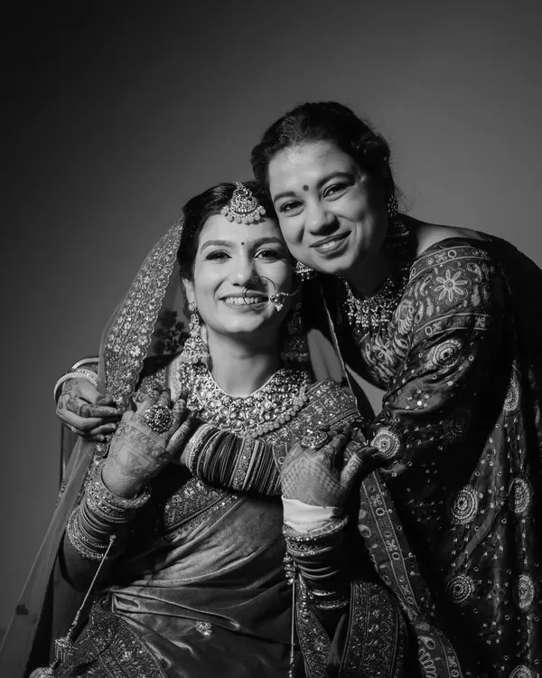 A heartwarming black and white portrait of the bride sharing a beautiful, smiling moment with her mother. This candid shot captures the precious bond and emotion of the wedding day.