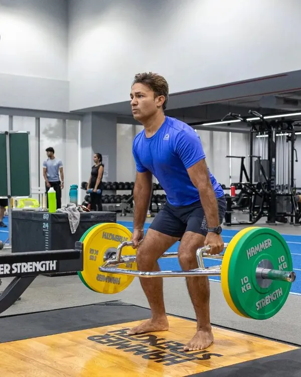 A runner performs a trap bar deadlift, an excellent exercise for building lower body and core strength, which is fundamental for powerful running. Our program incorporates key lifts to build a strong foundation.