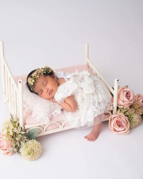 A perfect little angel asleep on a tiny bed, surrounded by flowers. This is a classic newborn setup that I love to create. The delicate lace outfit and floral details make it a truly timeless portrait.