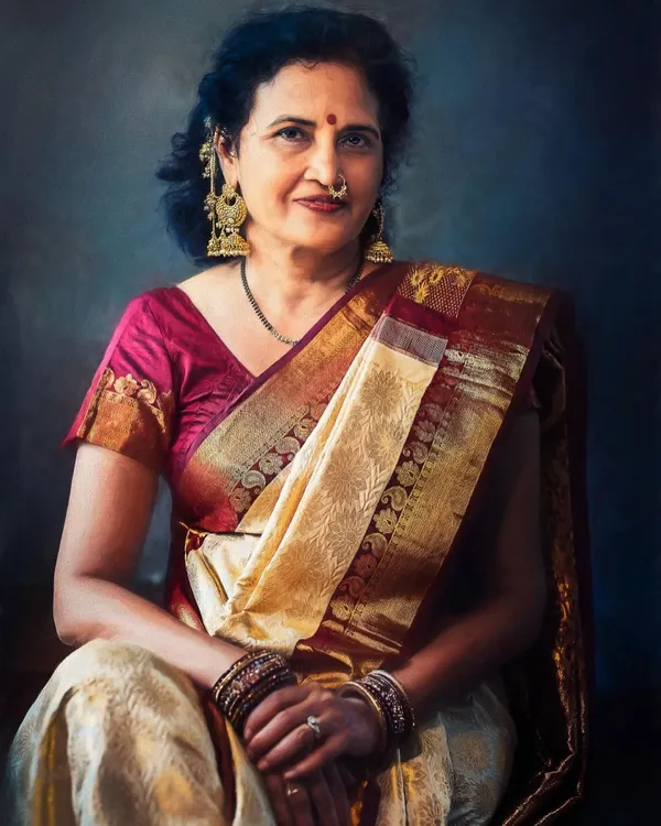 A portrait capturing the quiet dignity of a mother dressed in a traditional silk sari. The soft lighting and painterly background highlight her classic jewelry and serene expression, creating a timeless family treasure.
