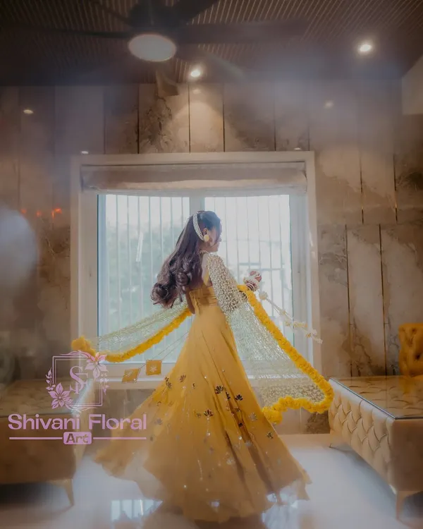 A beautiful bride twirling in her Haldi outfit, adorned with a full set of my floral creations. The look includes a stunning jasmine bud dupatta with a marigold border, heavy kalire, and matching floral handcuffs.