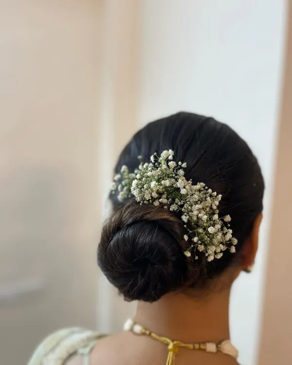 A classic and elegant low bun adorned with delicate baby's breath. This timeless hairstyle is perfect for a sophisticated look for a wedding or reception.