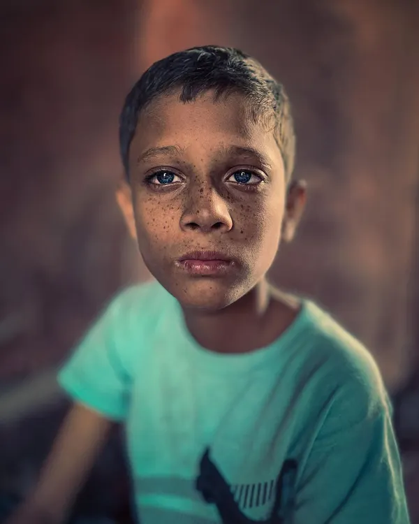 A striking close-up portrait of a child with freckles and intense blue eyes, his direct and soulful gaze creating a powerful connection.