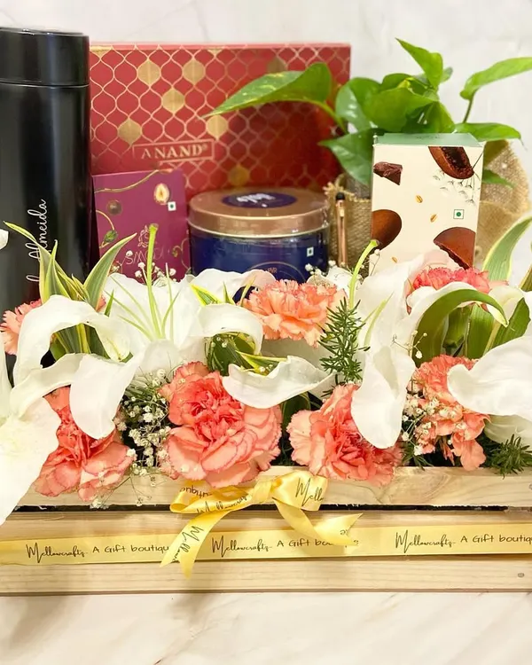 A luxurious wooden crate hamper overflowing with fresh lilies, carnations, and a live plant. This stunning arrangement is paired with premium chocolates and a personalized flask for an unforgettable gift.