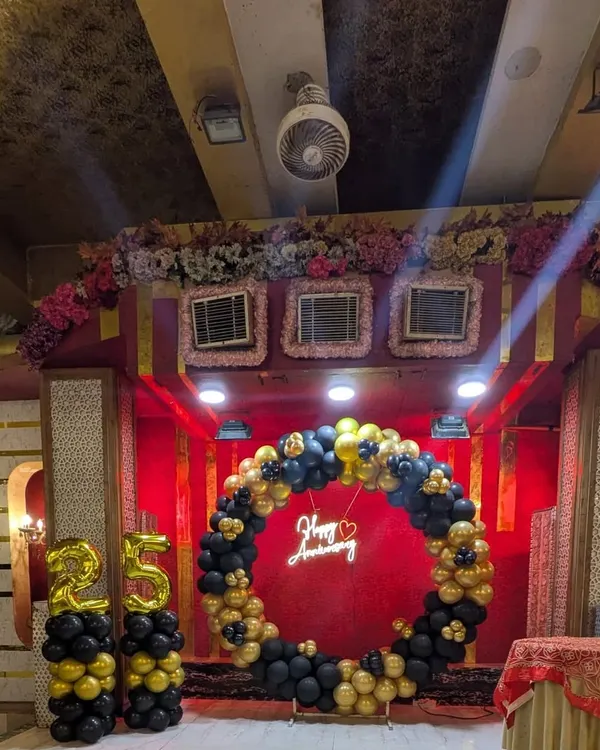 A full view of the stage setup for a 25th-anniversary party. The circular balloon arch, neon sign, and "25" balloon pillars create a sophisticated and celebratory focal point.