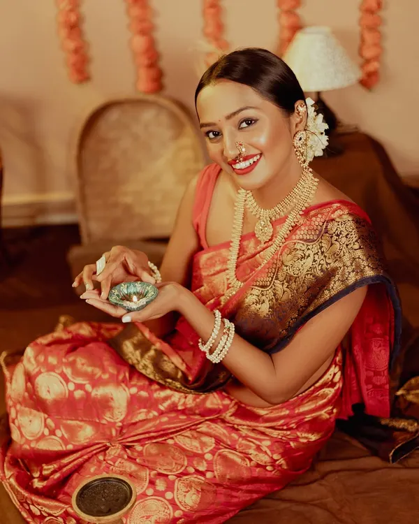A beautiful portrait of a woman holding a lit diya, her smile illuminated by its warm glow. This shot captures the serene and happy essence of Diwali.