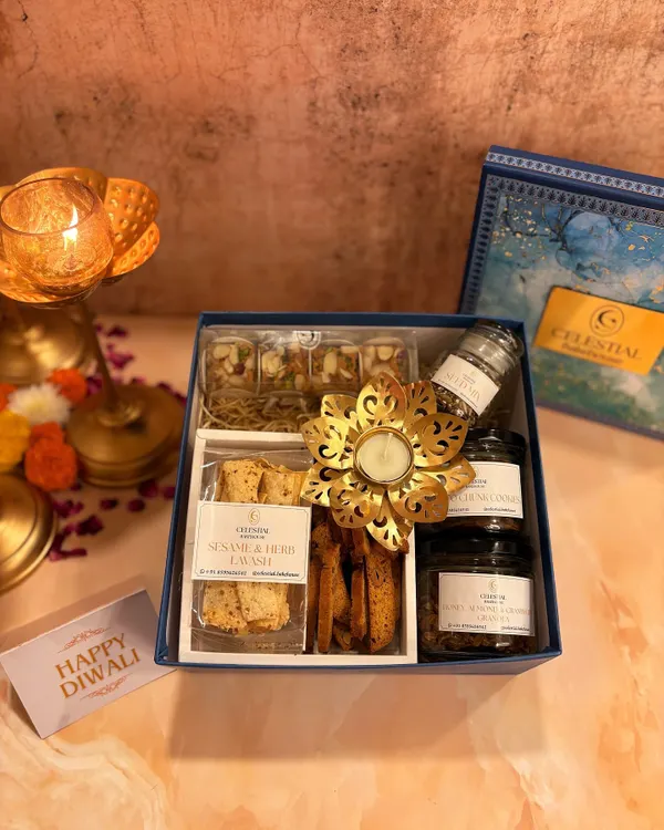A glimpse into our festive Diwali collection. This gift box features our sesame and herb lavash, assorted healthy sweets, and a decorative diya, all presented in an elegant blue box.