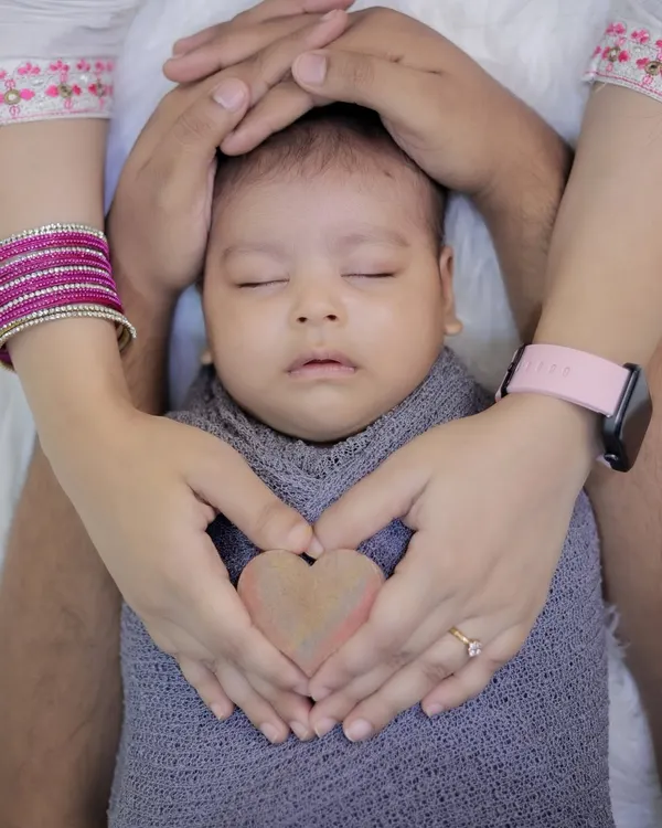 A classic newborn pose, with parents' hands forming a heart around their sleeping baby. This shot symbolizes the bubble of love and protection surrounding your new arrival.