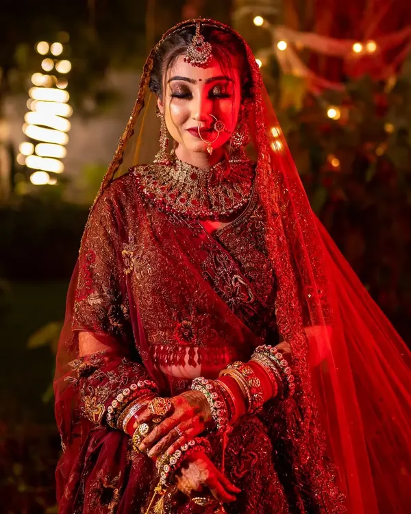 A breathtaking bridal portrait with dramatic red lighting and a soft focus, highlighting the bride's regal presence and intricate jewelry.