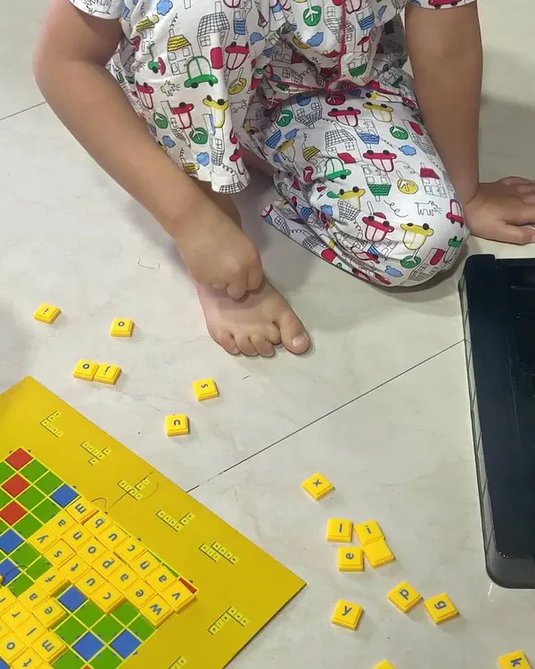 We make learning words a game, not a chore. Using a simple Scrabble board, we practice spelling and reading three and four letter words. It’s a playful way to build vocabulary and early literacy skills right on the living room floor.
