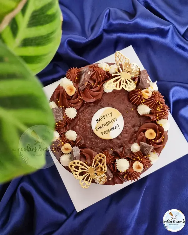 My Triple Chocolate Ganache Brownie Cake is pure indulgence. This 7-inch walnut brownie base is lavishly decorated with different chocolate frostings, hazelnuts, and delicate golden butterflies.